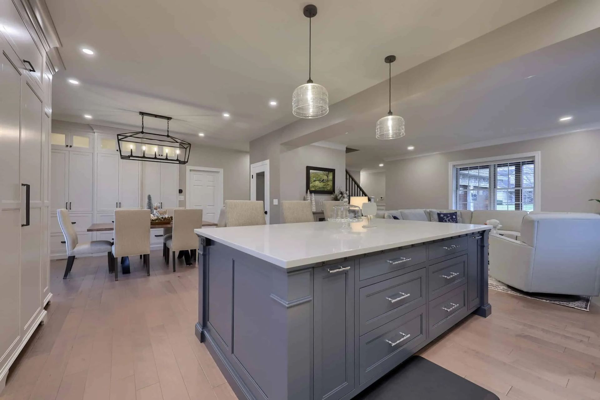 Open-concept kitchen and dining room with gray island, white counters, and pendant lights