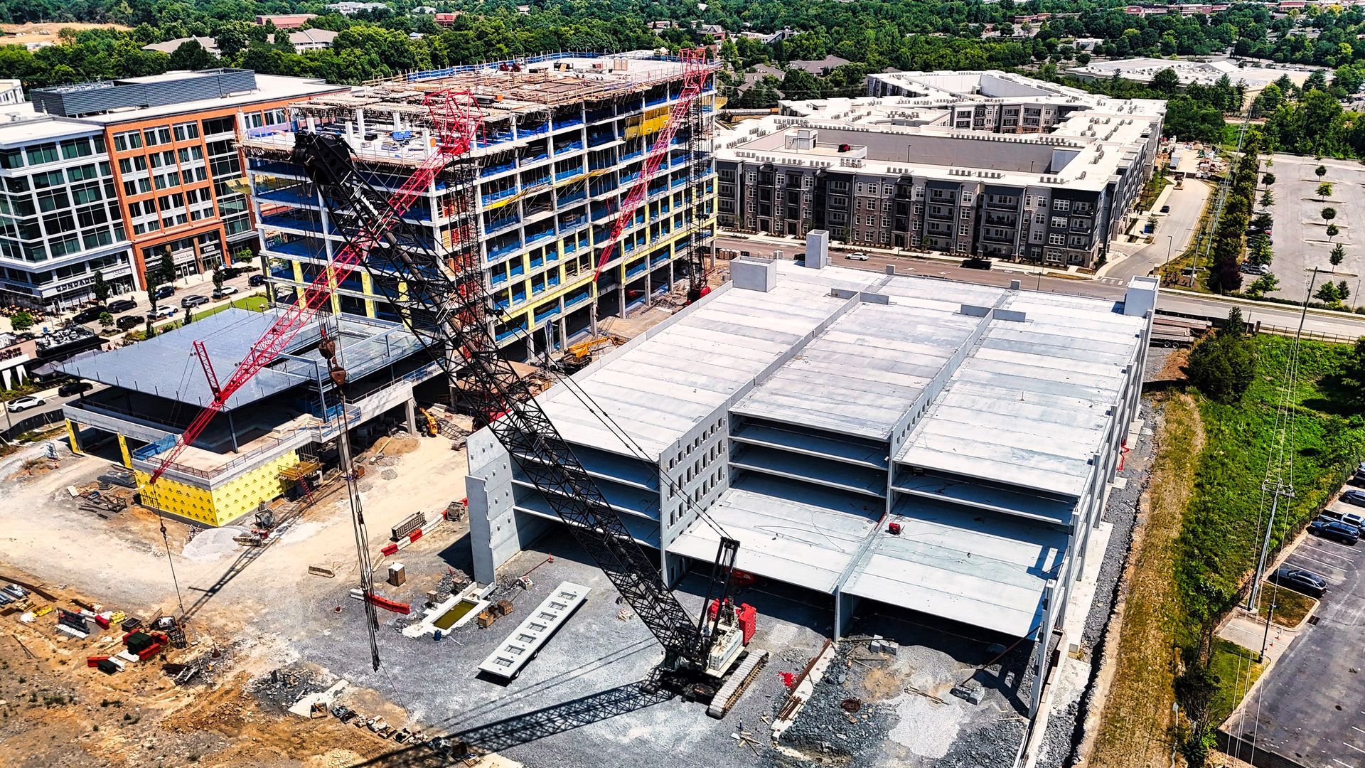 Aerial view of a large construction site with several partially built multi-story buildings and cranes