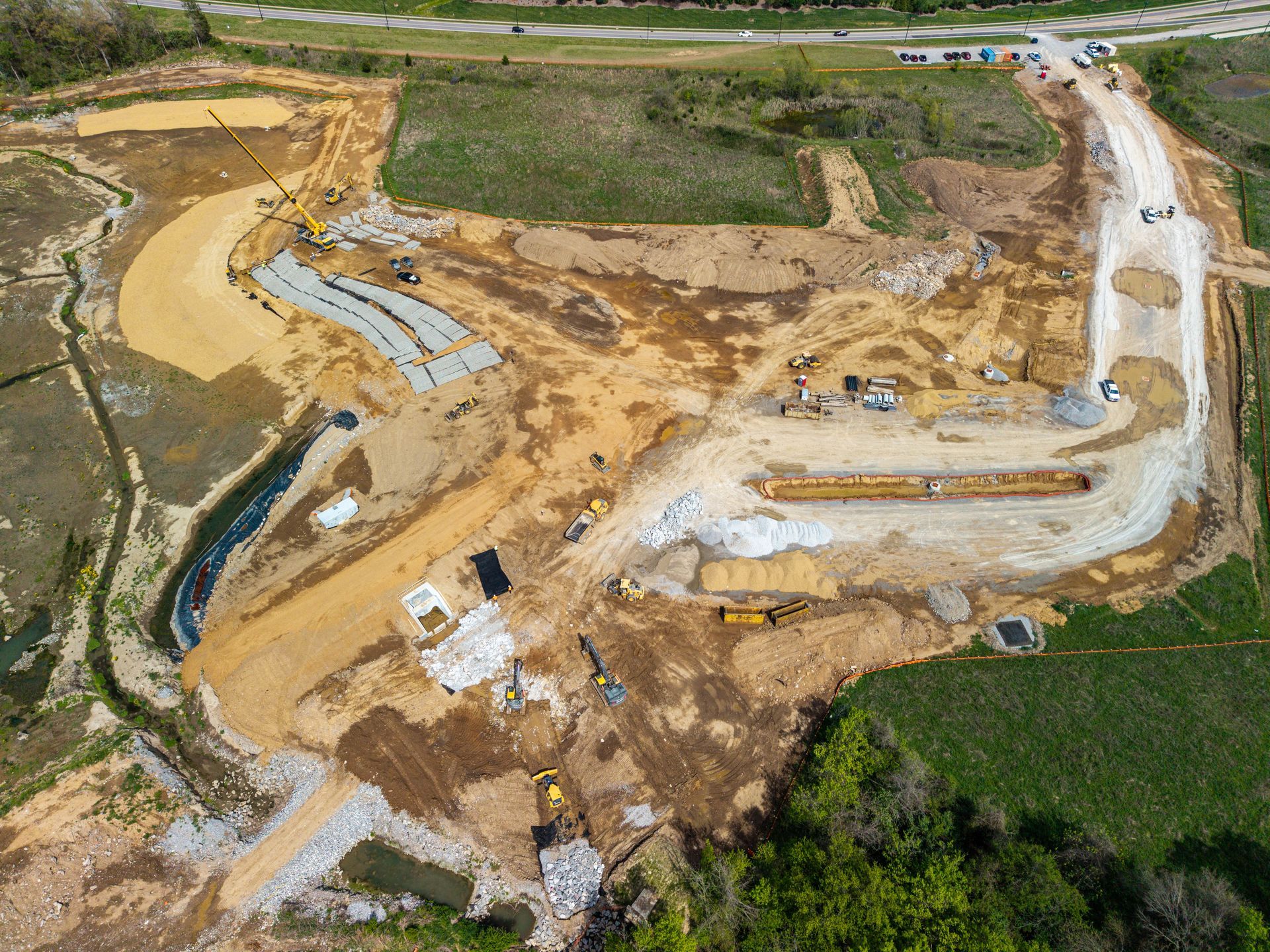 Aerial view of a large construction site with dirt roads, excavated earth, and heavy machinery.