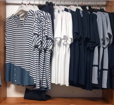 Un negozio pieno di vestiti appesi sugli scaffali.