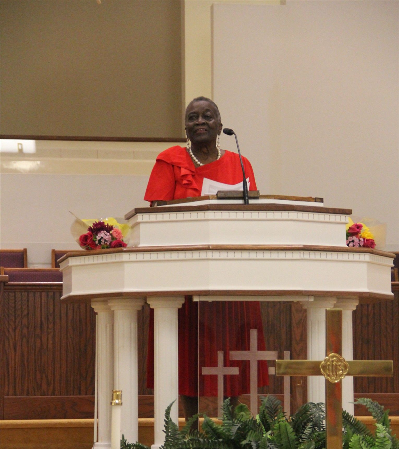 A woman is holding a basket of candy in front of a table full of candy.