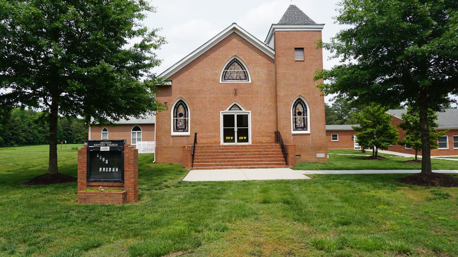 A brick church with a sign in front of it
