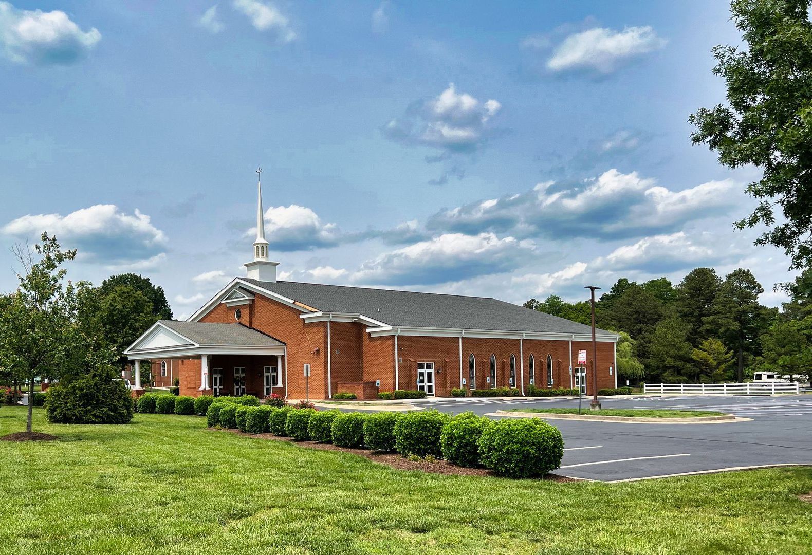 Exterior of Antioch Baptist Church in Varina, showing the red-brick building with steeple and landscaped grounds.