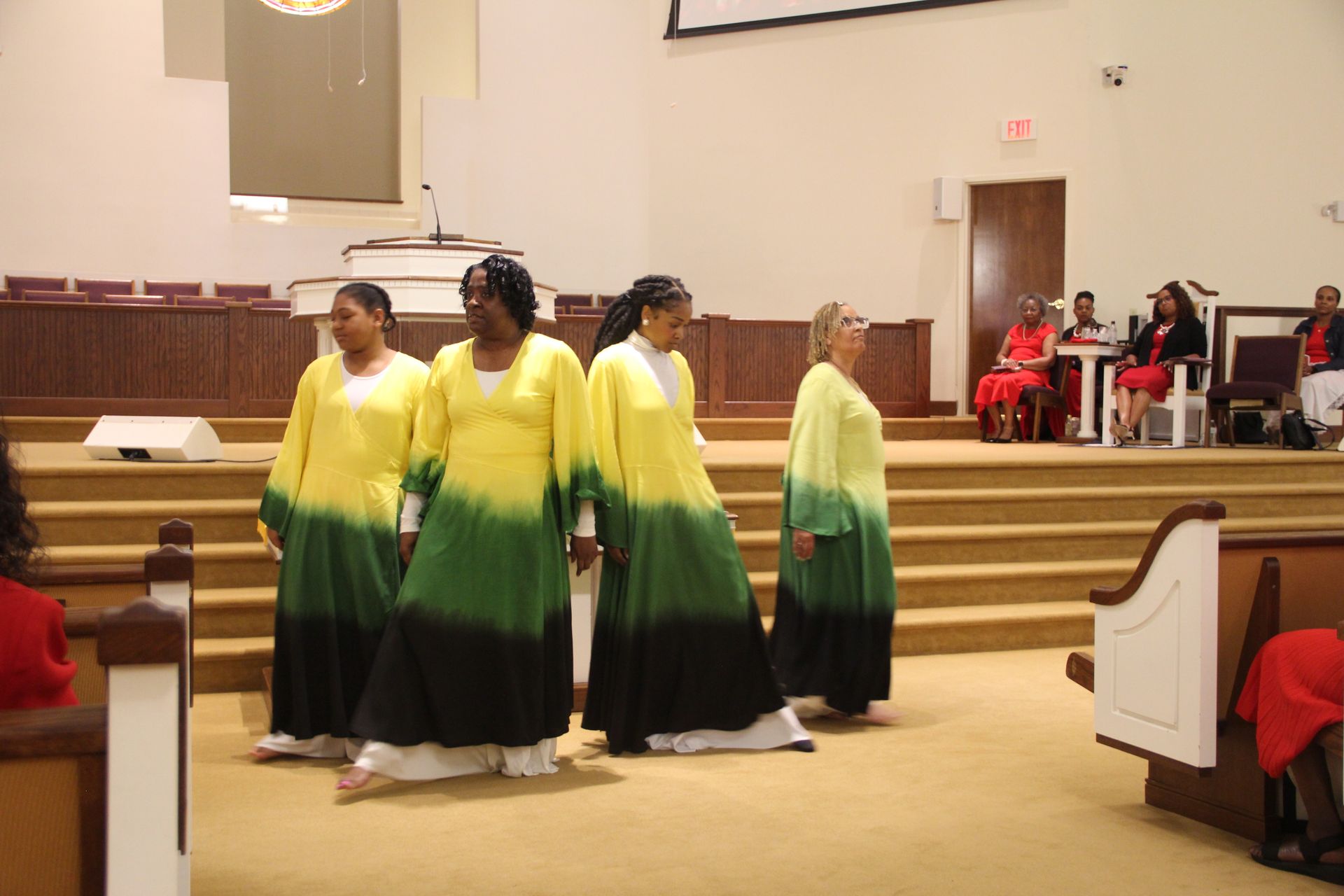 Pastor Paul D. Flowers Sr. in a black robe stands next to Rev. Flowers in a suit holding a microphone