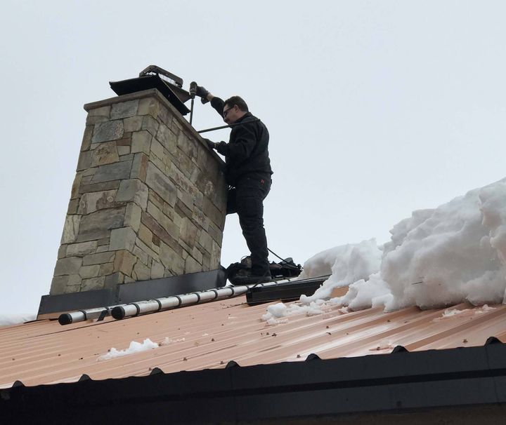 A man is working on a chimney on top of a roof.