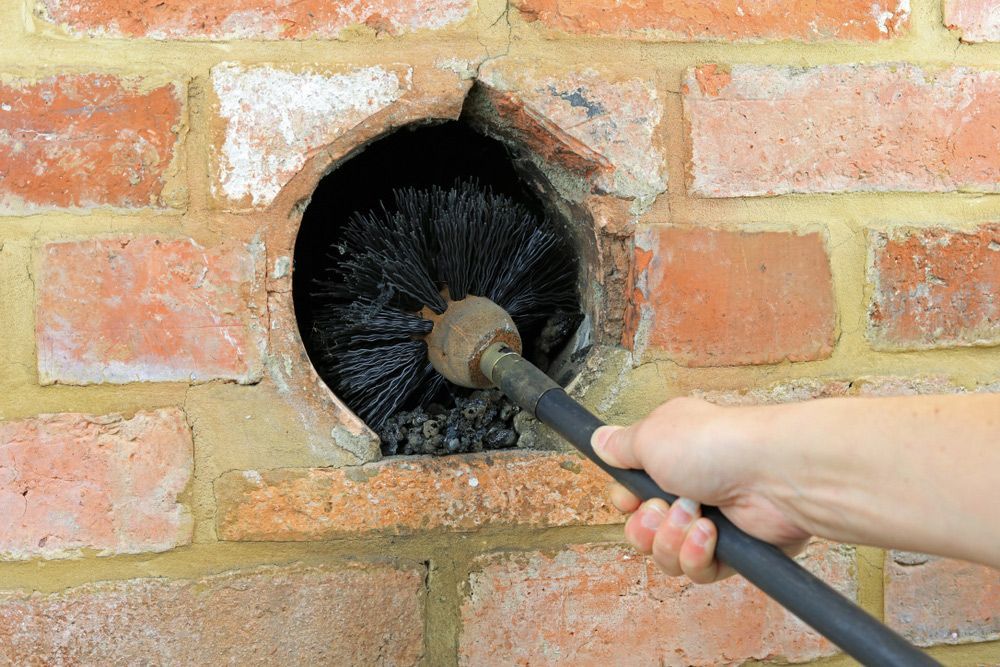 A person is cleaning a brick wall with a brush.
