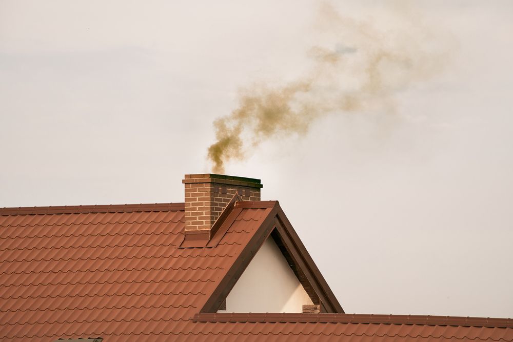 Smoke is coming out of a chimney on the roof of a house