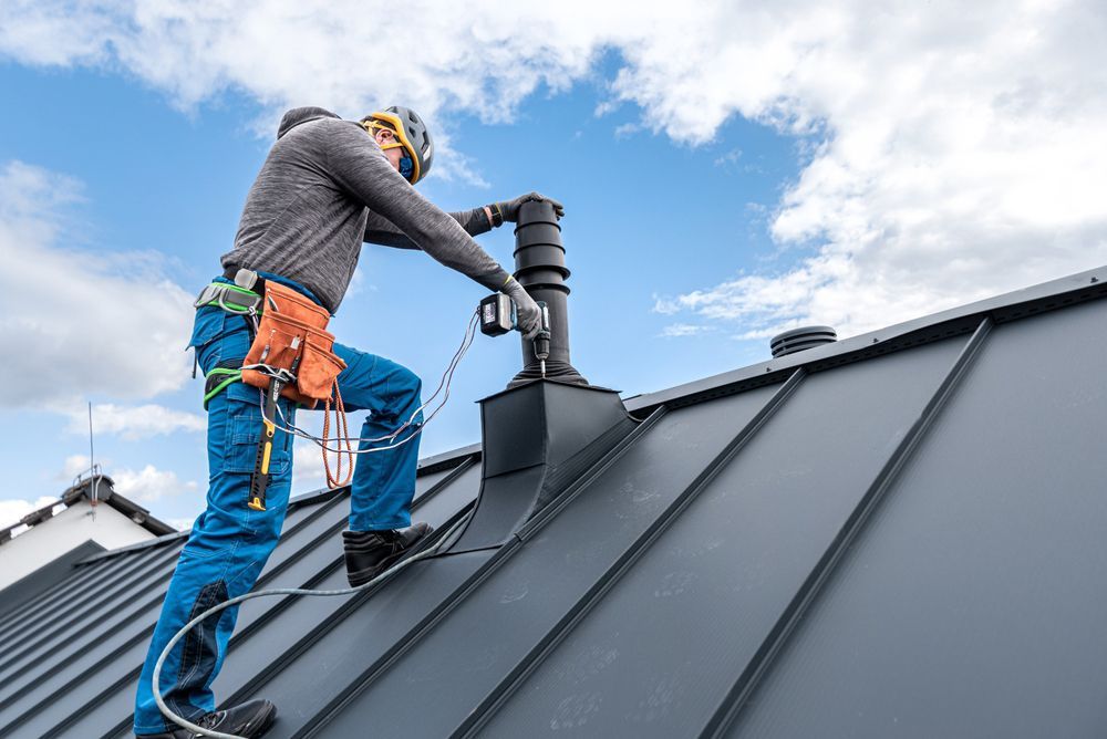 A man is standing on top of a roof fixing a chimney.