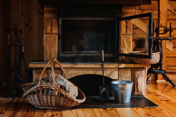 A fireplace with a basket of logs in front of it.