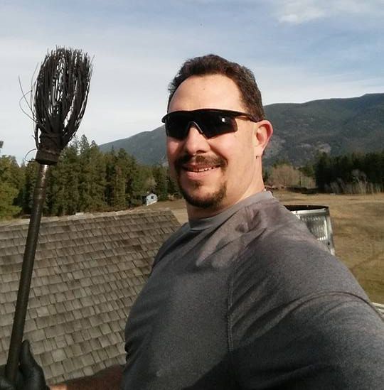 A man wearing sunglasses is holding a broom and smiling