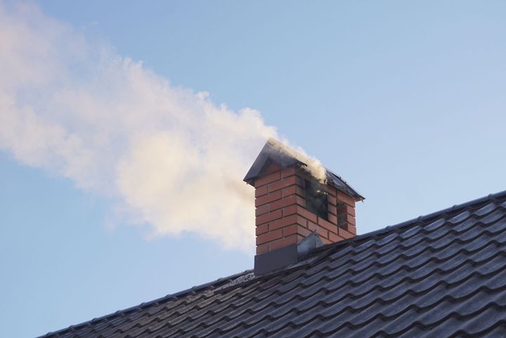 Smoke is coming out of a chimney on top of a roof.