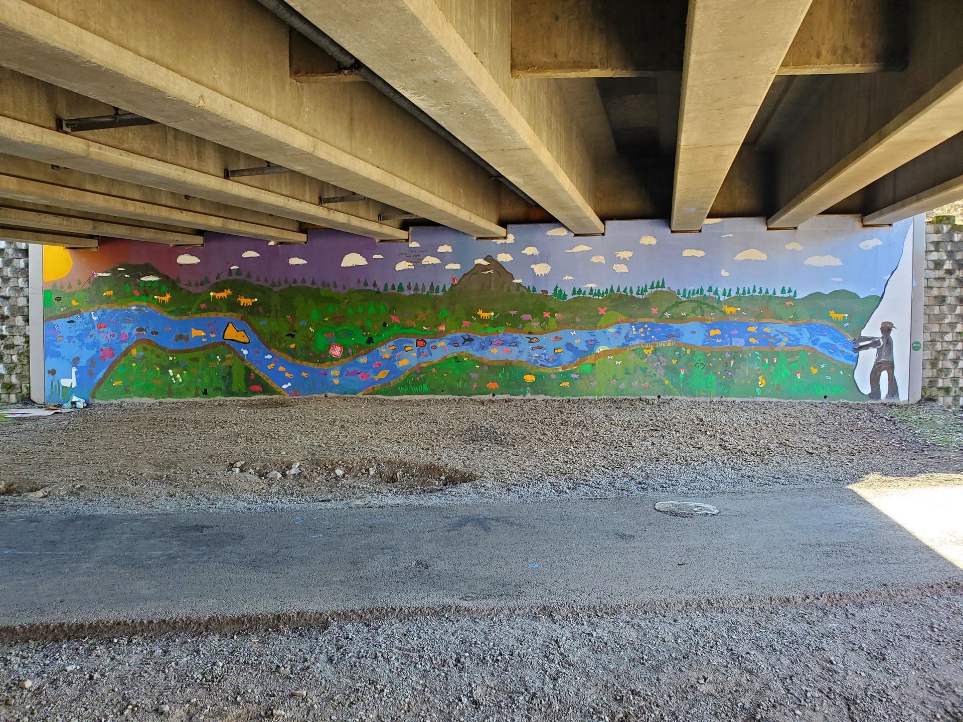 A wall painting of a river and mountains under a bridge.