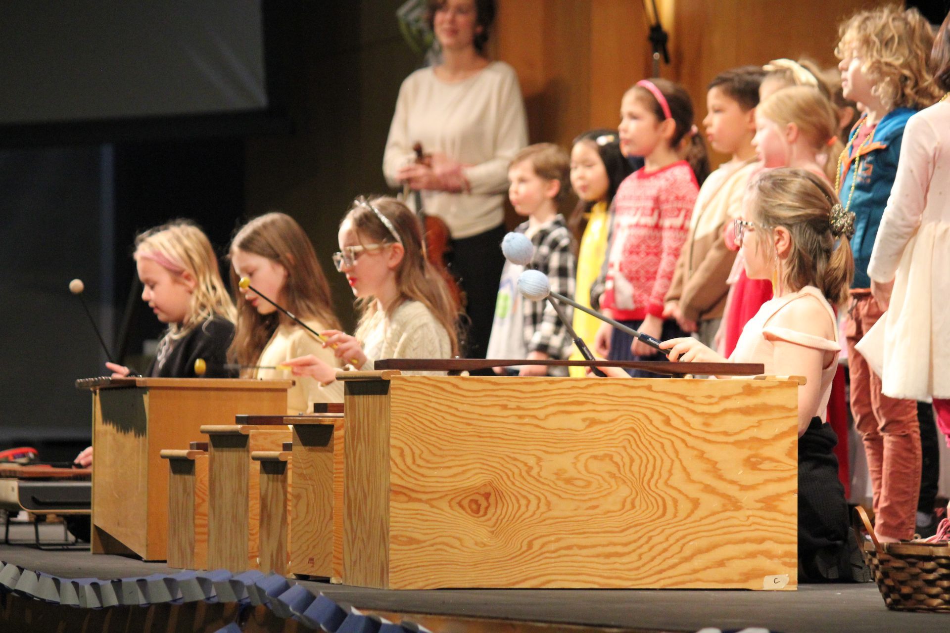 A group of young girls are playing xylophones on a stage.