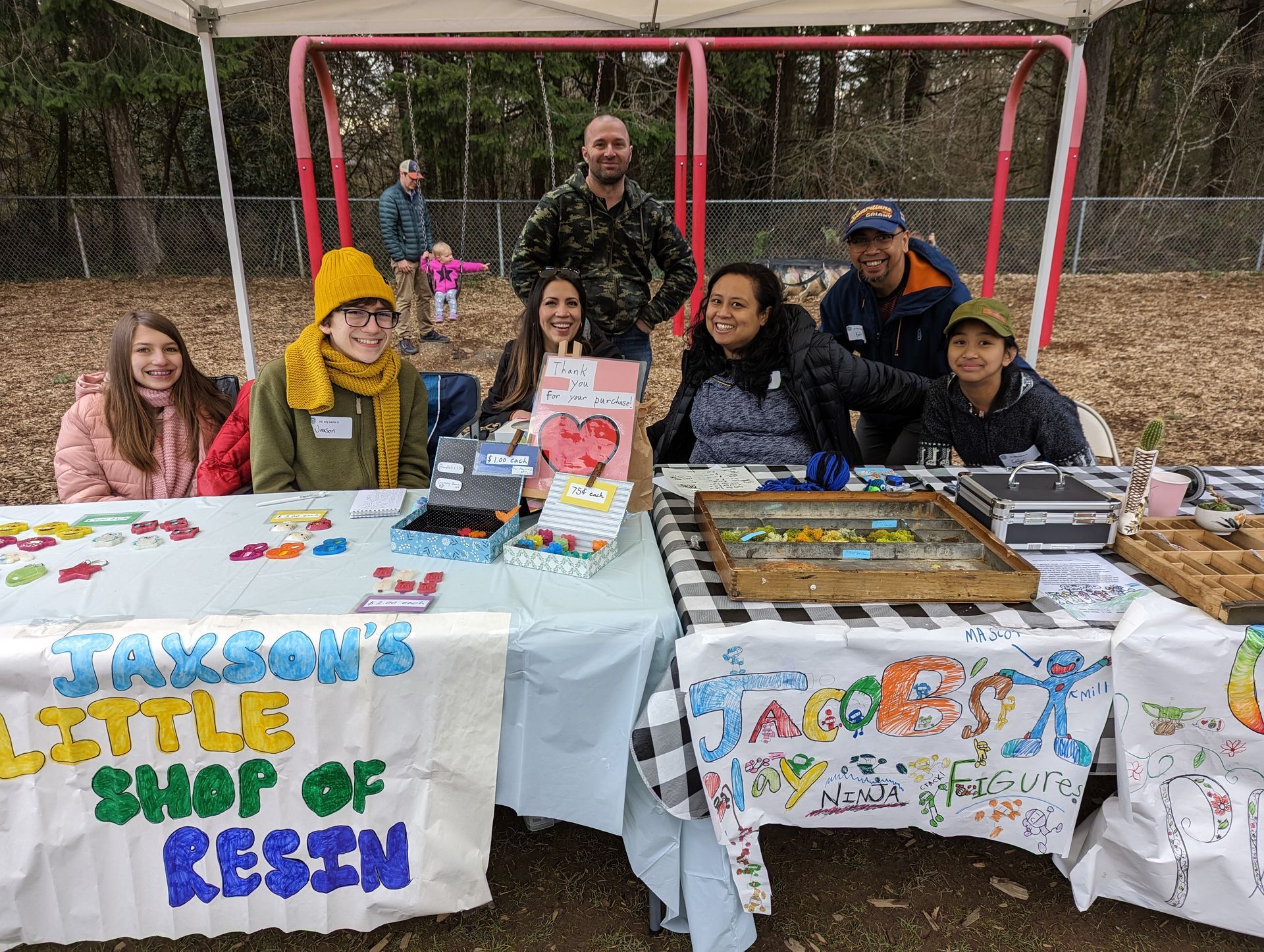 A group of children are sitting in sales stands in a park