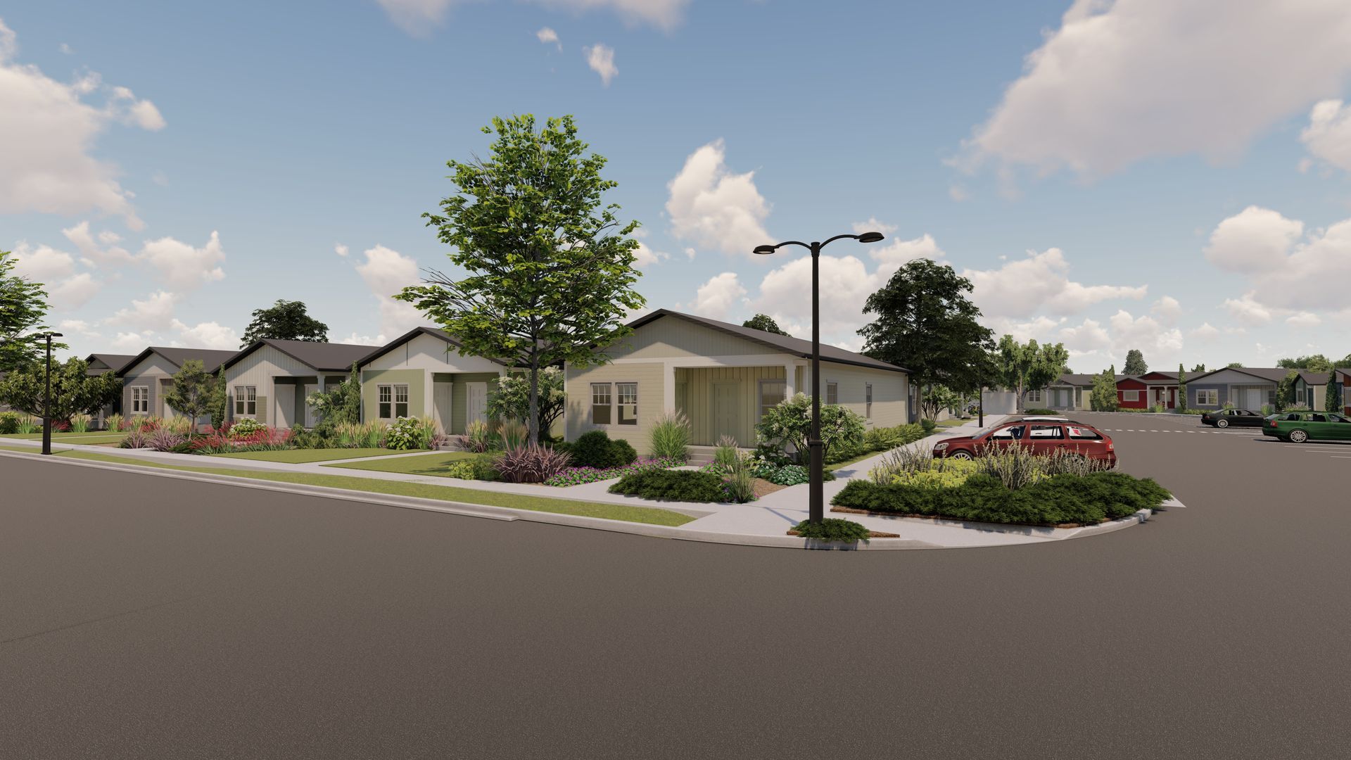 Suburban housing development with single-story homes, streetlights, trees, and a landscaped roundabout under a cloudy sky