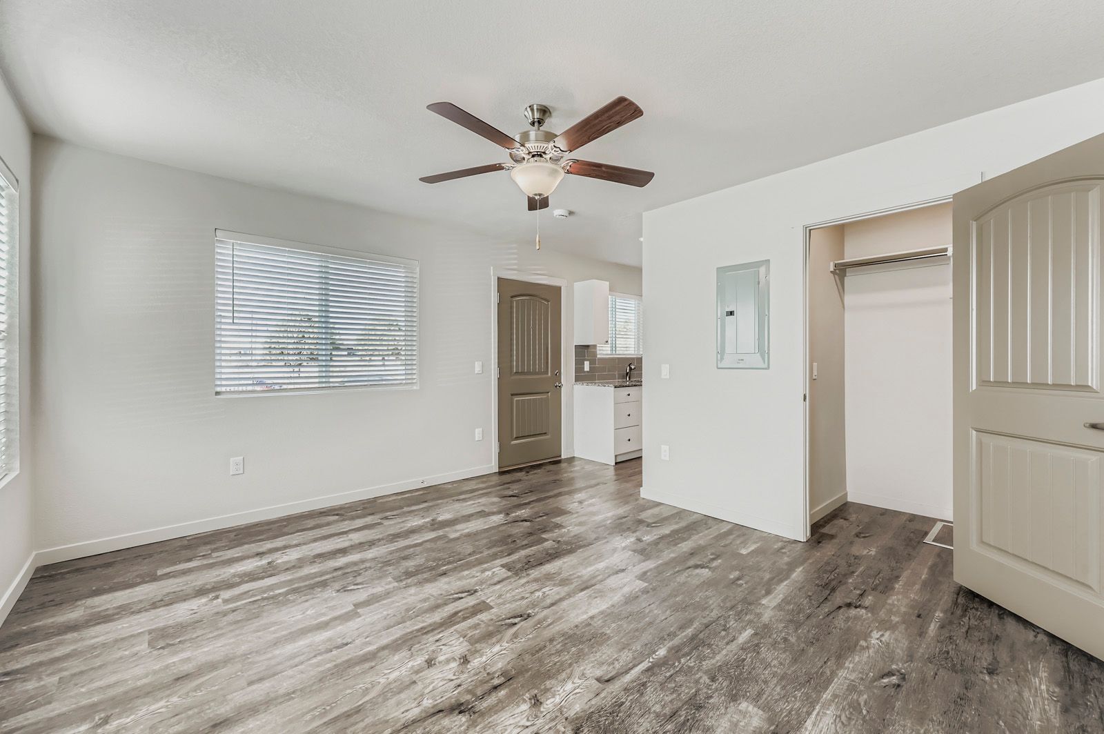Empty room with gray wood floors, ceiling fan, window, and open closet door