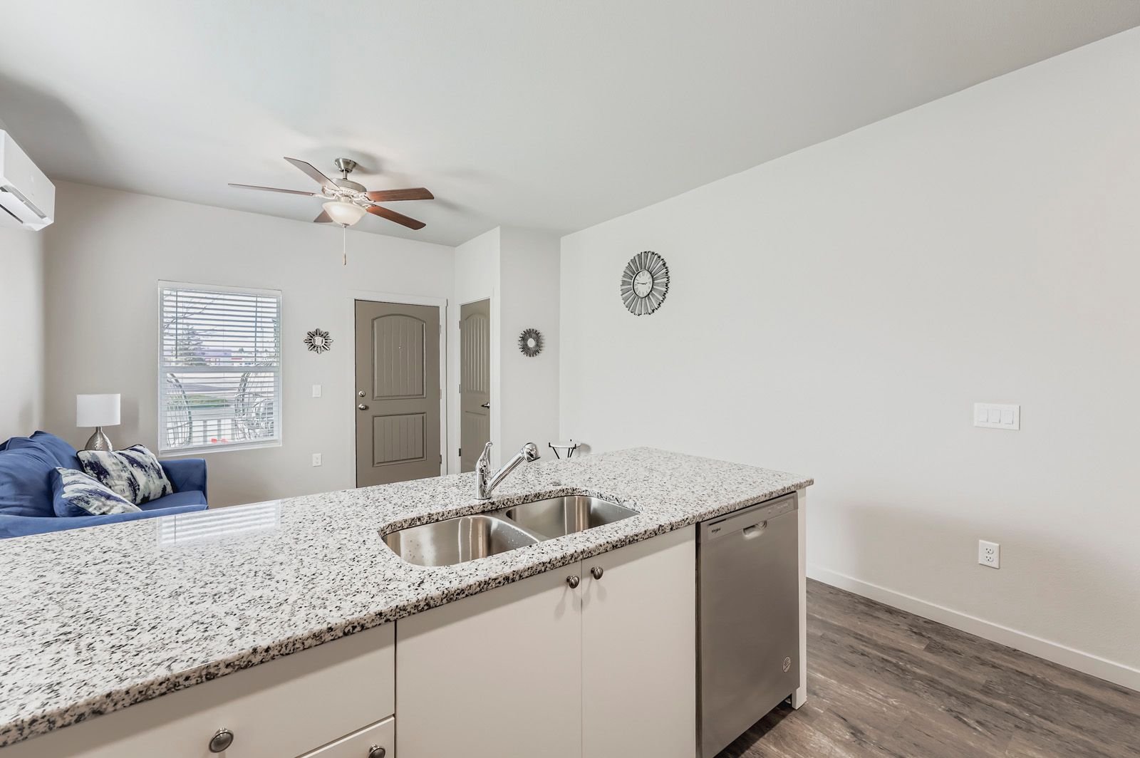 Modern kitchen with speckled island countertop opening to a bright bedroom and hallway