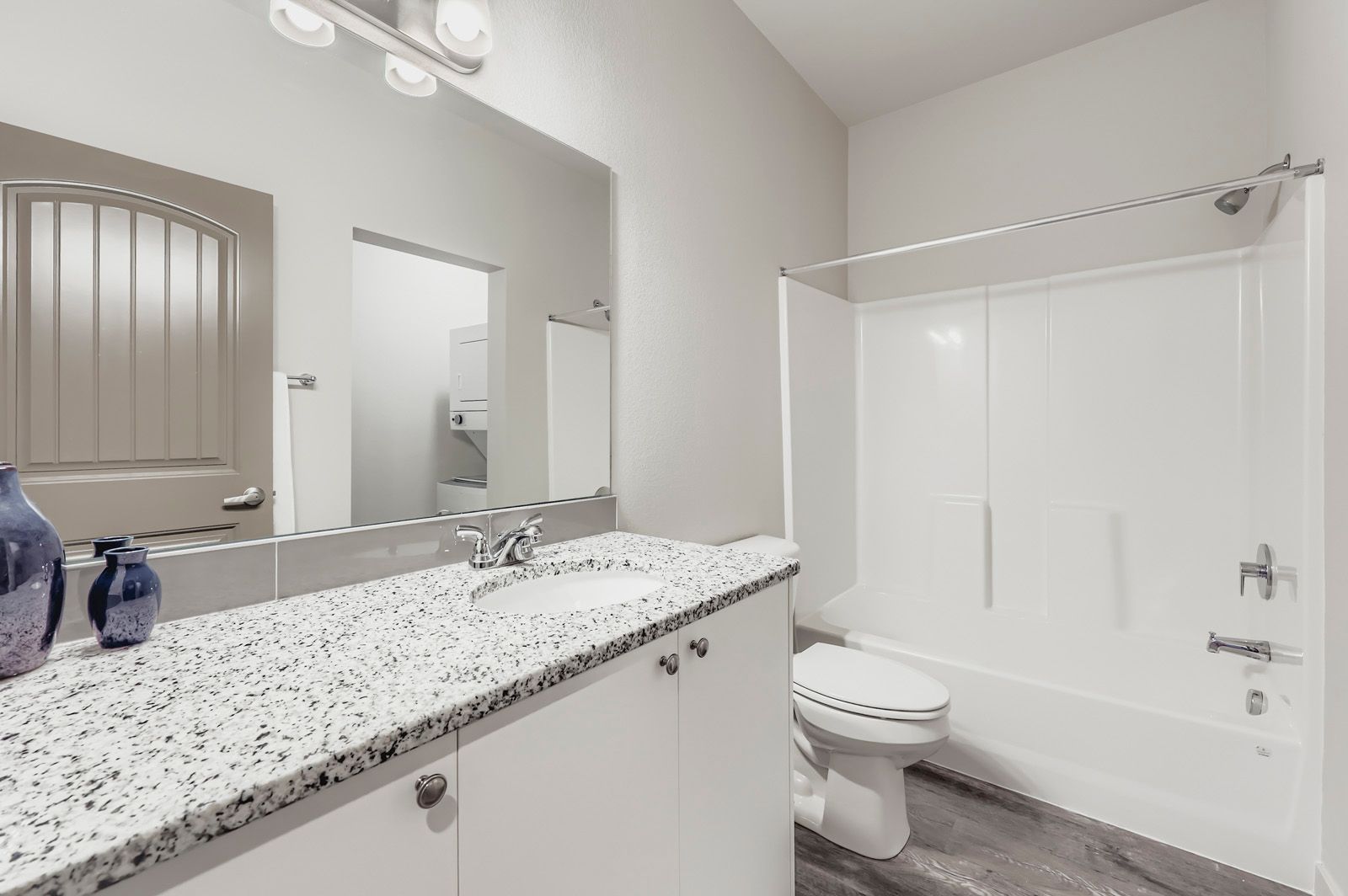 Modern bathroom with granite vanity, mirror, toilet, and white shower stall