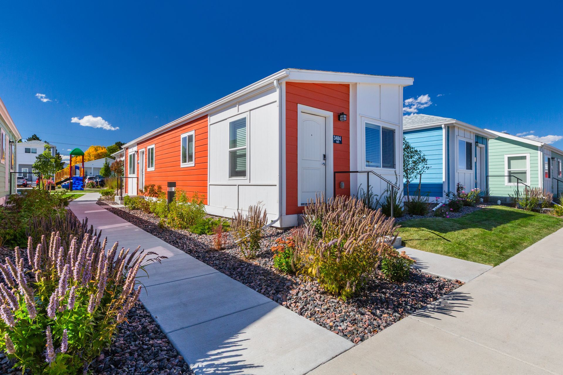 Bright colorful tiny houses along a paved walkway in a sunny residential community