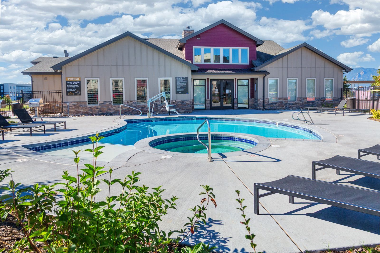 Modern building with a blue pool and lounge chairs on a sunny patio