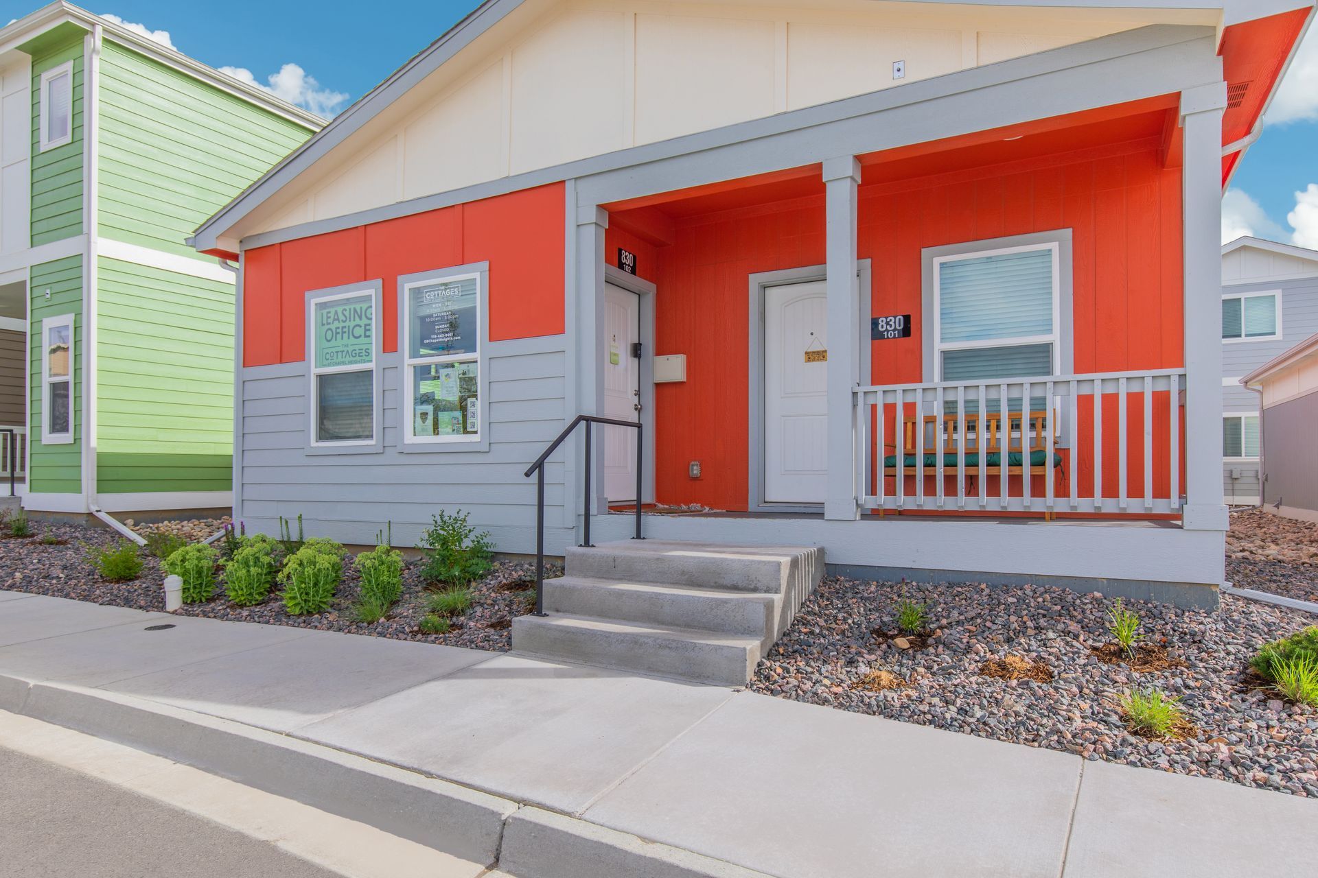 Bright orange and gray single-story house with a small front porch and steps along a residential street.