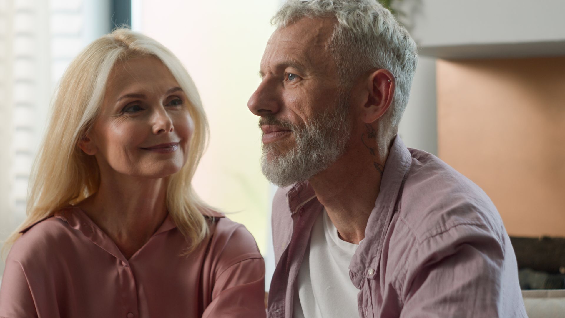 Two people smiling at each other in a softly lit indoor setting