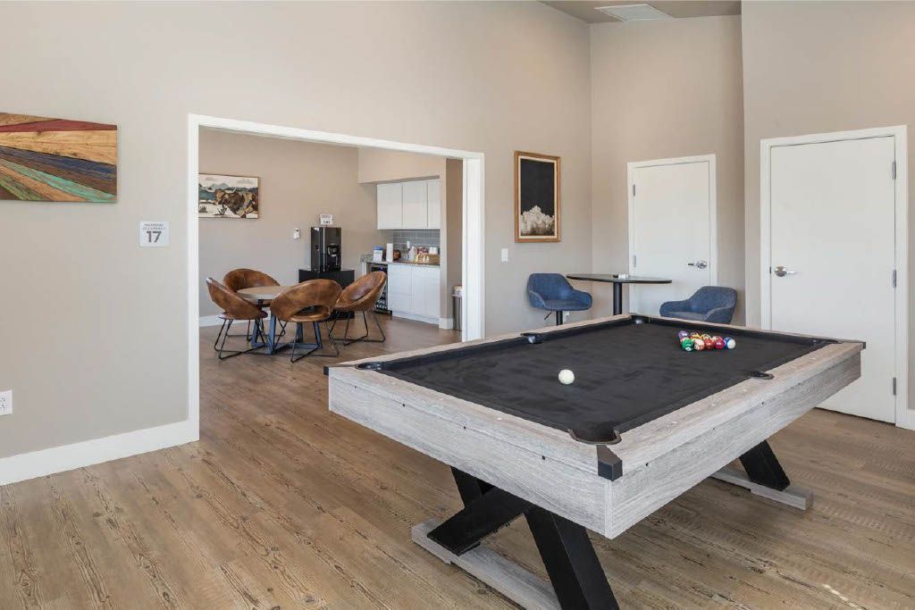 Game room with a pool table, chairs, and large open doorway to a dining area