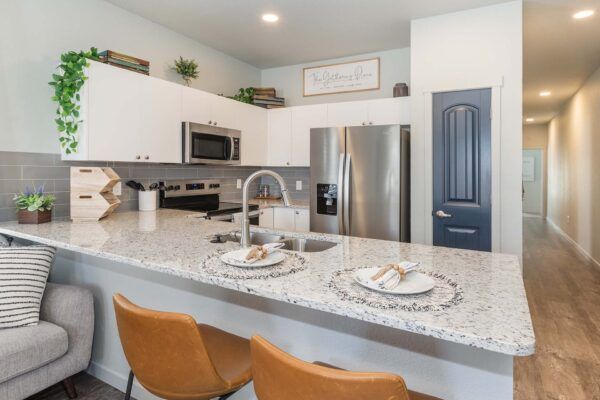 Modern kitchen with white island, stainless steel appliances, blue pantry door, and breakfast seating