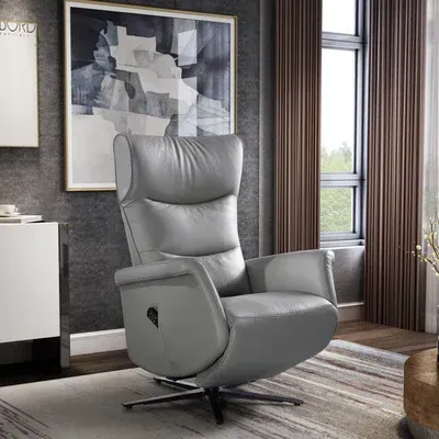 Een grijze leren relaxfauteuil staat in de woonkamer naast een raam.