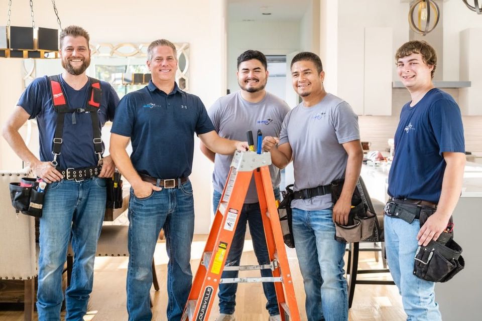 Five electricians standing with tools and ladder in a bright home interior