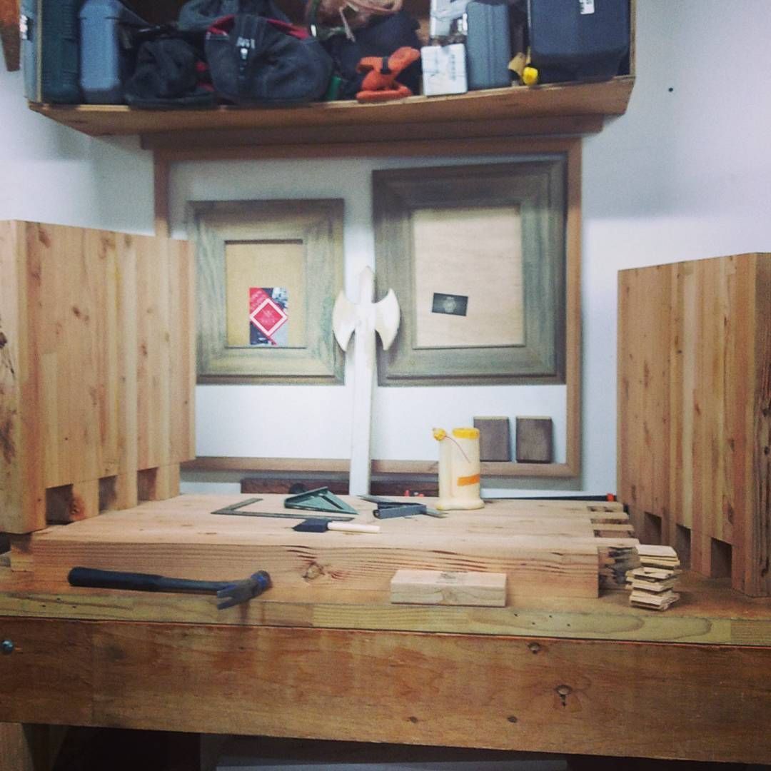 Wooden workbench with a partially built box. An axe shape stands on the bench, tools and glue nearby.