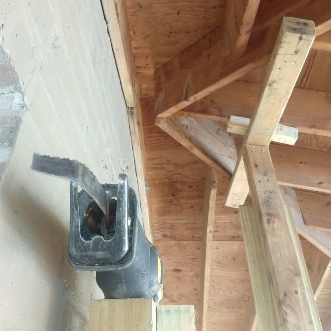 Saw blade cutting into wall under wooden structure.