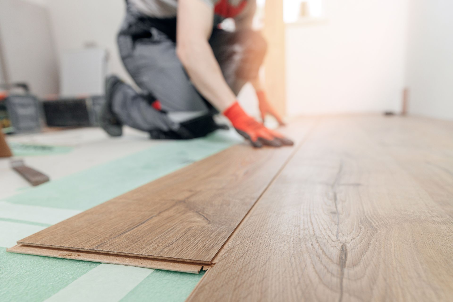 A man is installing a wooden floor in a room.