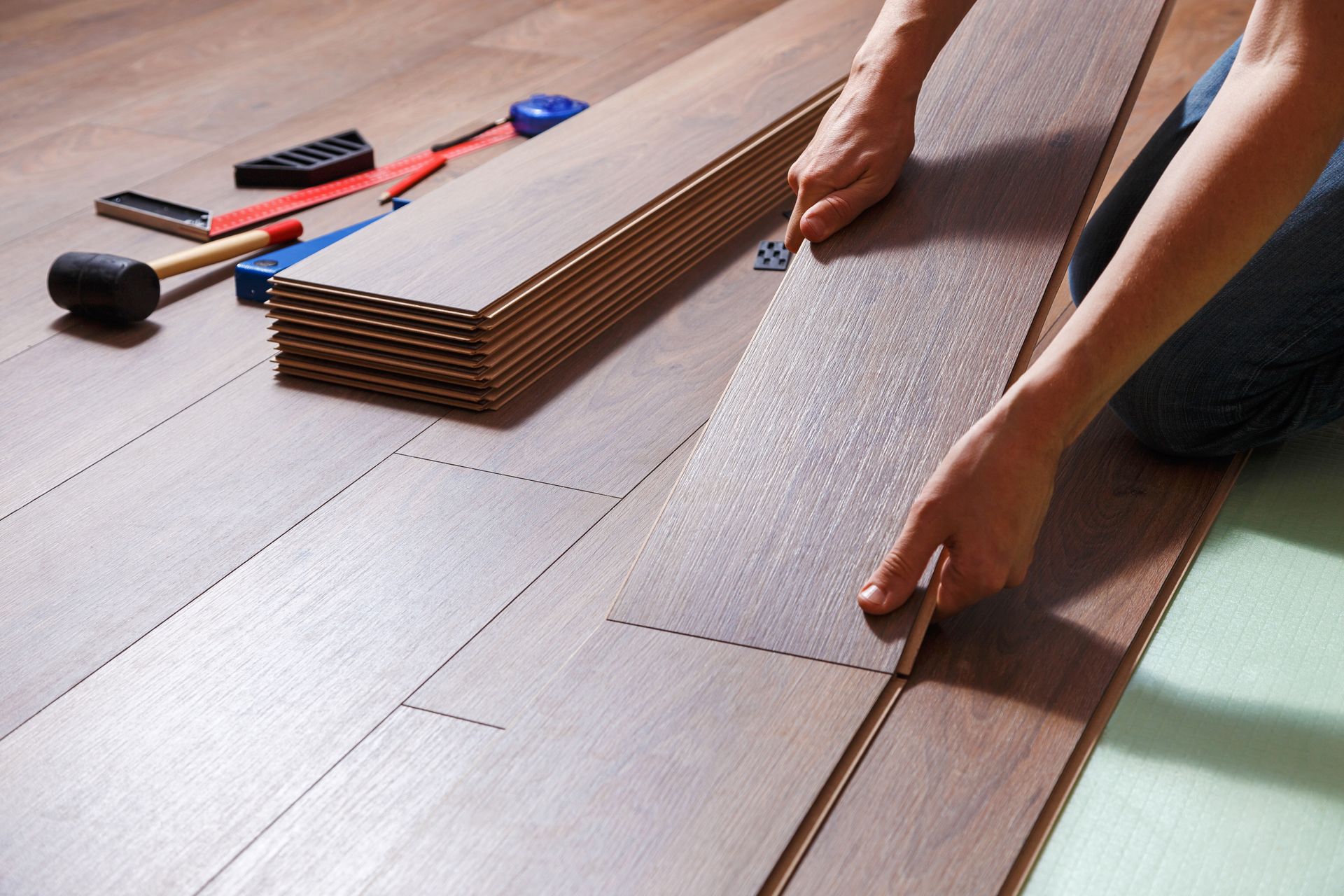 A person is installing a wooden floor in a room.