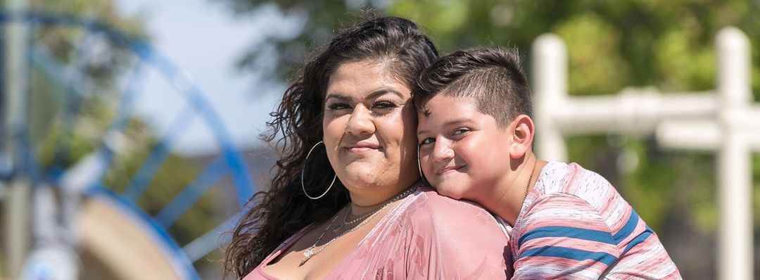 A woman and a boy are posing for a picture at a playground.