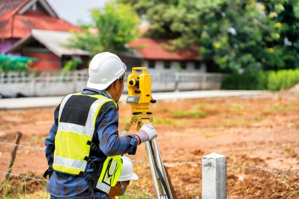 A Construction Worker Is Using a Theodolite on A Construction Site — Duggan Mather Surveyors in Singleton, NSW