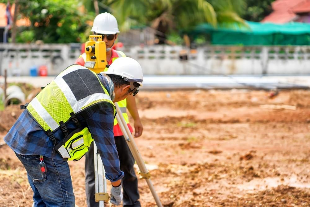 A Couple of Construction Workers Are Working on A Construction Site — Duggan Mather Surveyors in Wyong, NSW