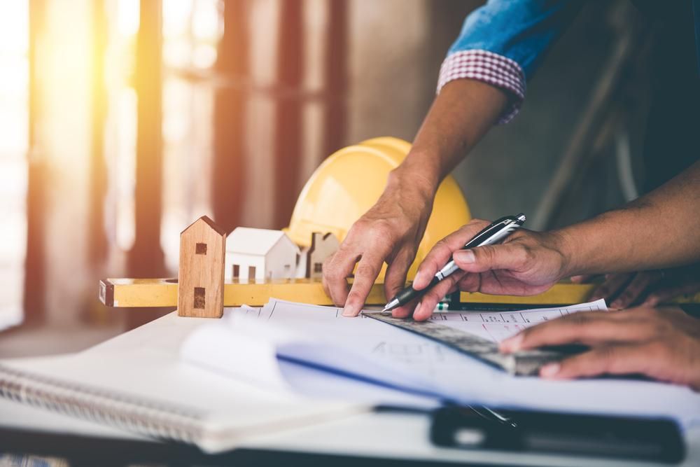 A Man Is Sitting at A Table Working on A Construction Project — Duggan Mather Surveyors in Taylors Beach, NSW