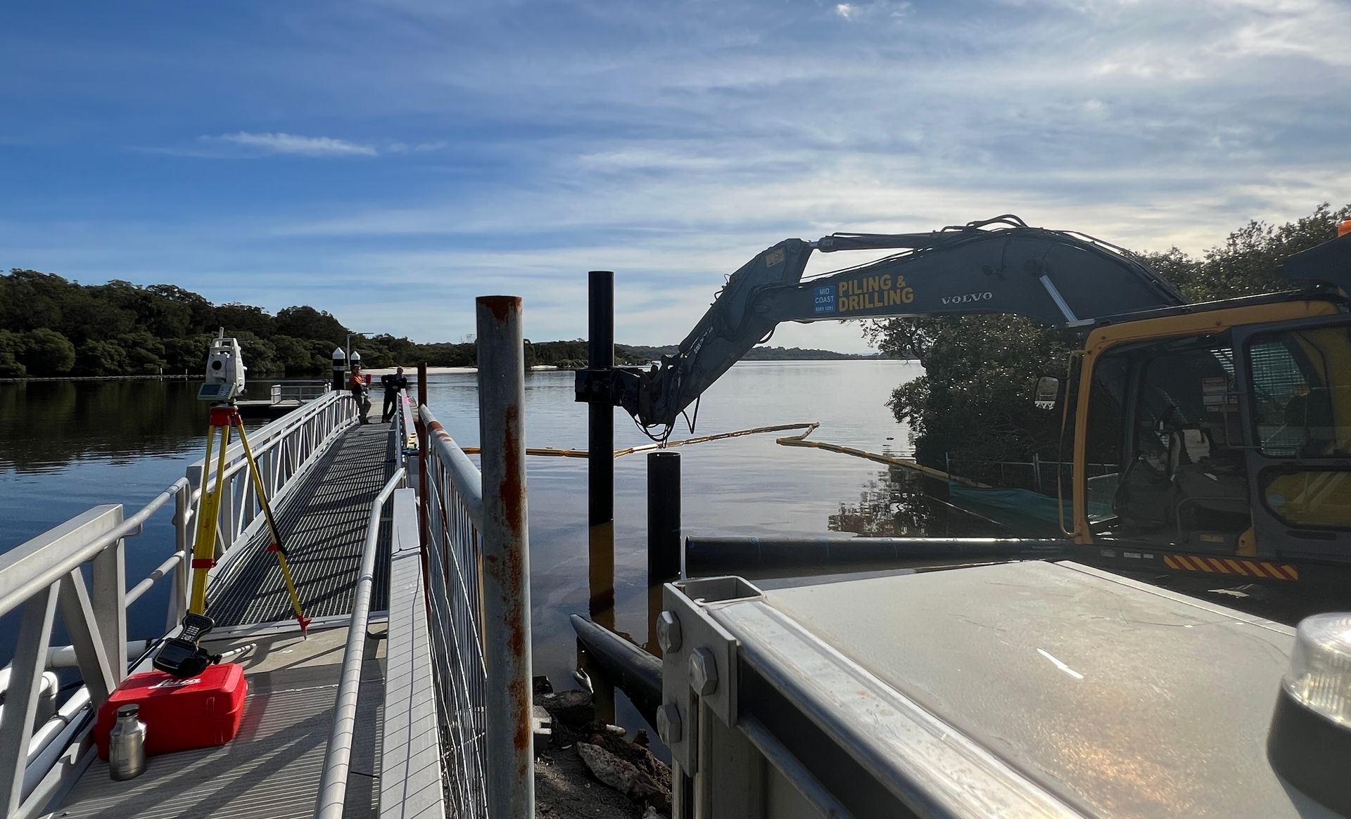A crane drilling in beam poles into an estuary— Duggan Mather Surveyors in Taylors Beach, NSW