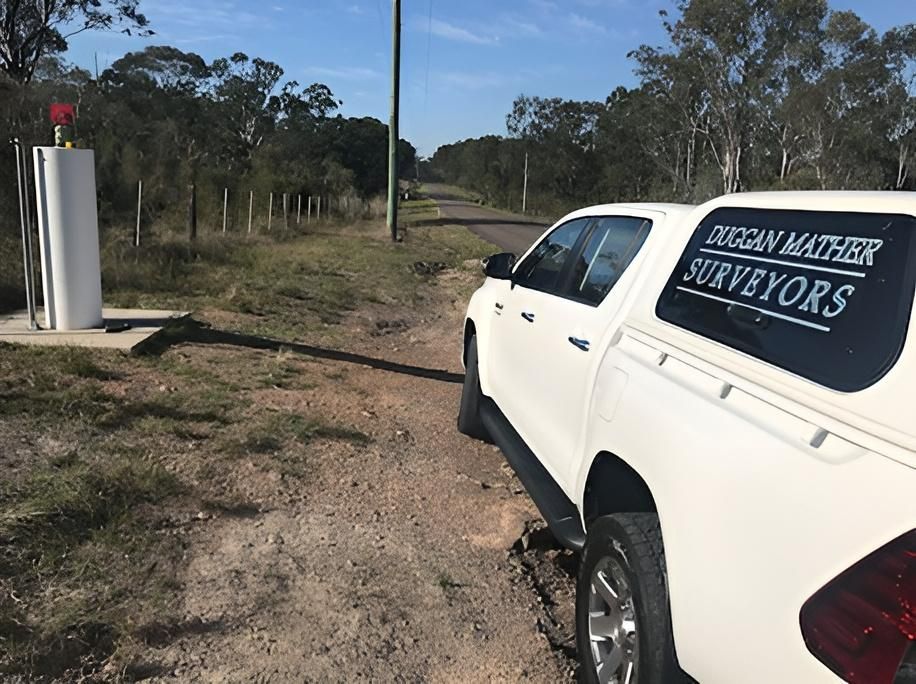 A White Truck with The Word Surveyors on The Side Is Parked on A Dirt Road — Duggan Mather Surveyors in Taylors Beach, NSW