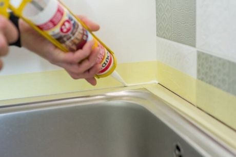 handyman sealing around sink