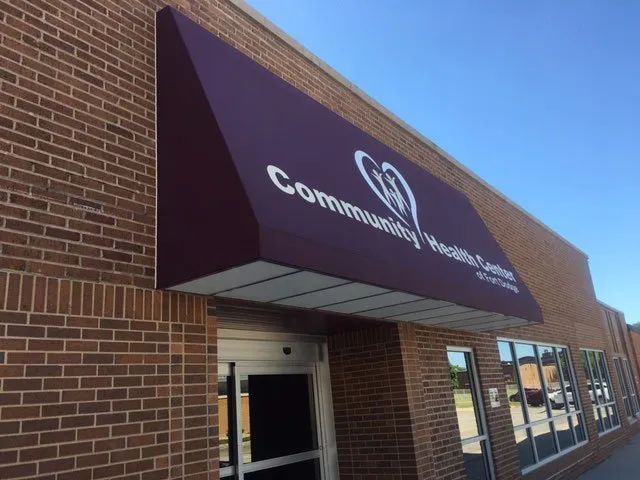 A brick building with a purple awning that says community health center.