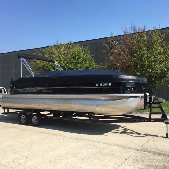 A pontoon boat is parked on a trailer in front of a building.