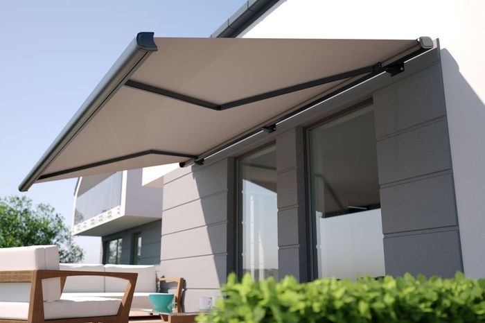 A white awning is covering a patio with chairs and a table.