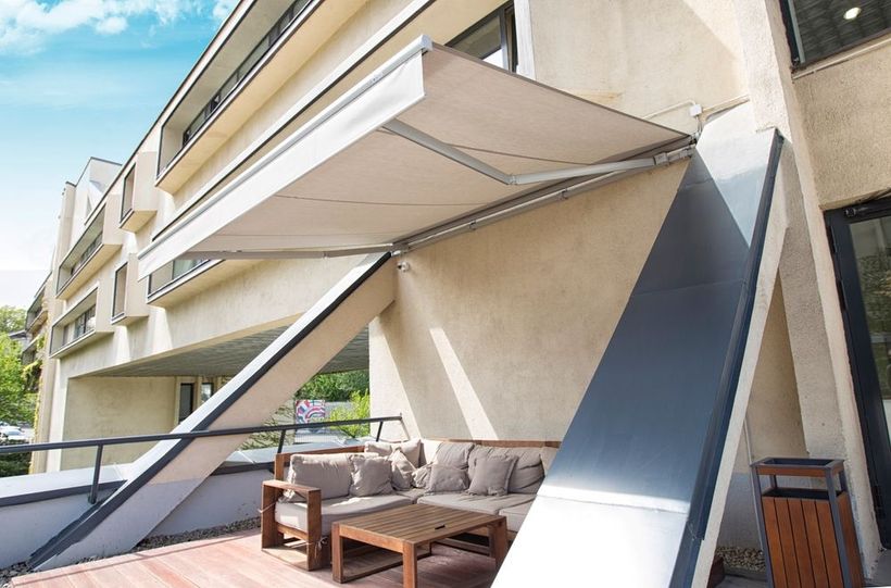 A balcony with a couch and a table under an awning.