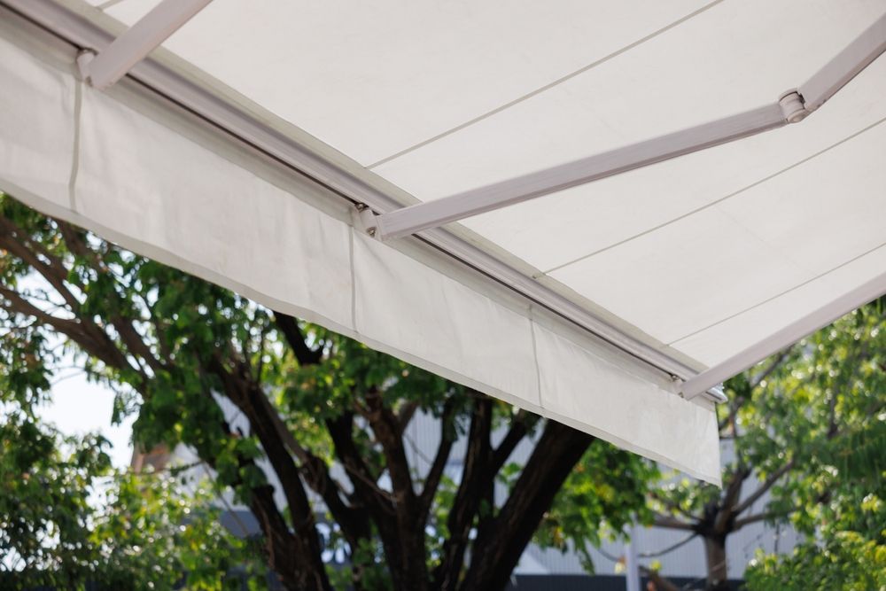 A white awning is hanging over a tree.