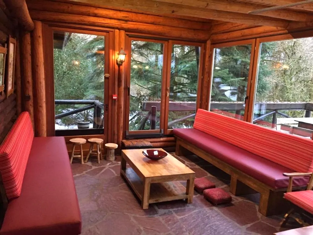 A living room with a couch , table and chairs in a log cabin.
