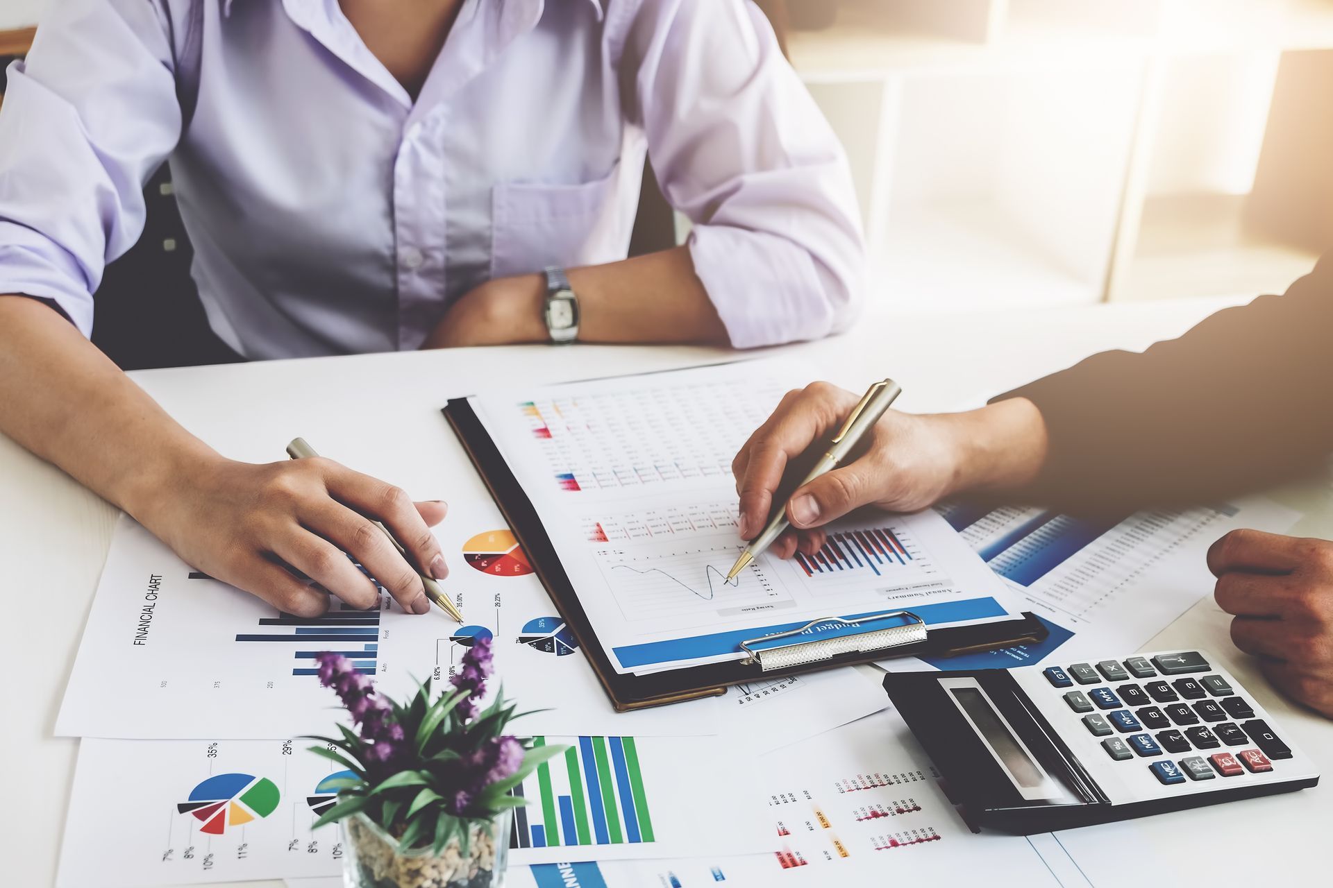 Two people reviewing financial charts and documents at a table.