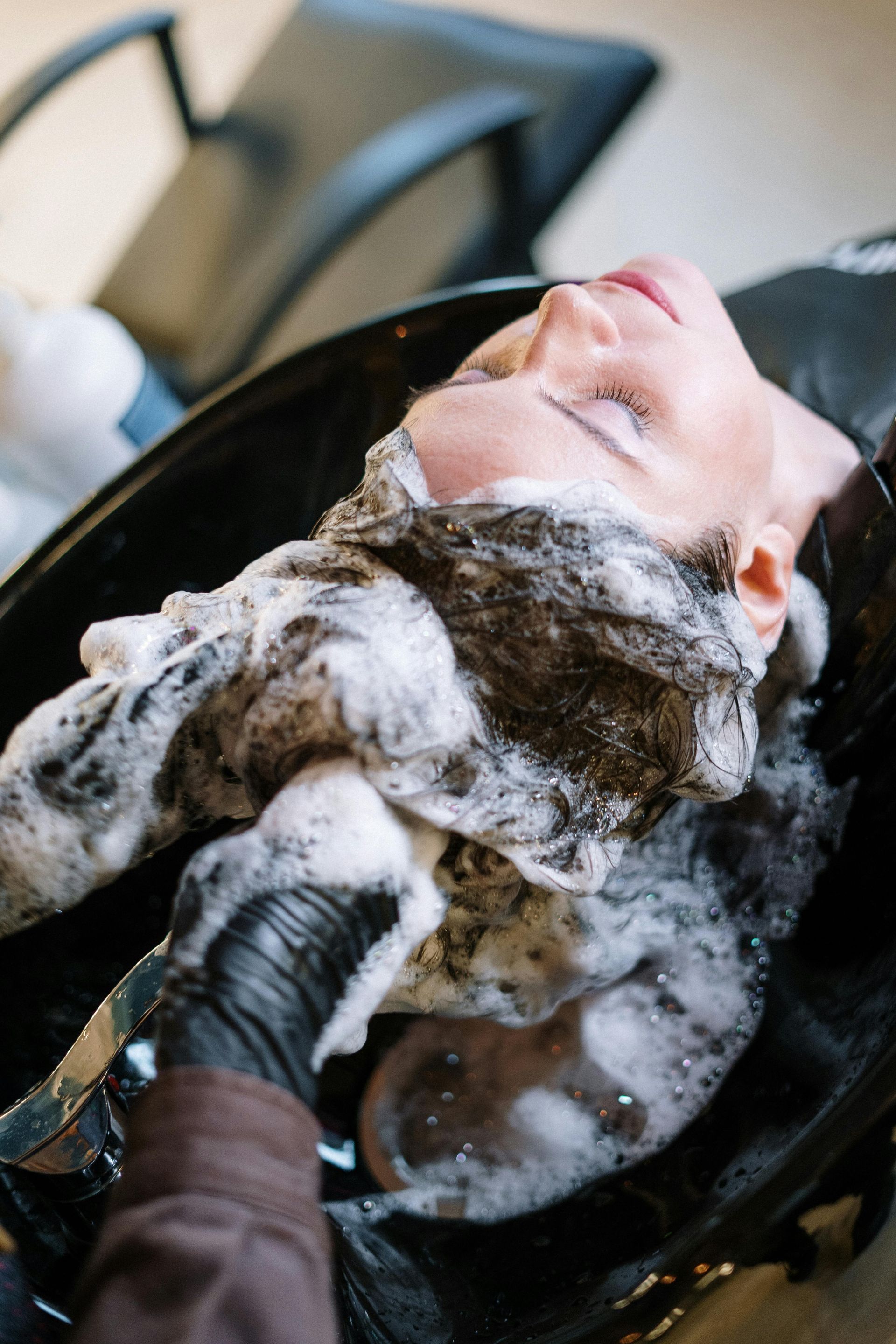 A woman is getting her hair washed in a sink at a salon.