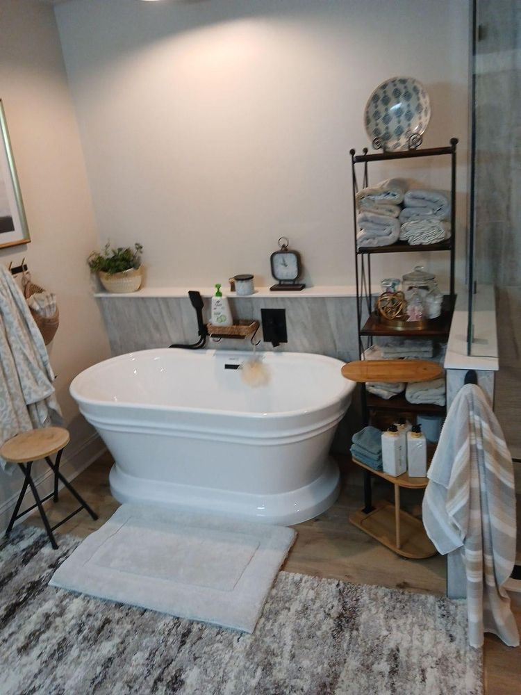 Bathroom with white oval tub, towels on shelves, and light-colored rug.
